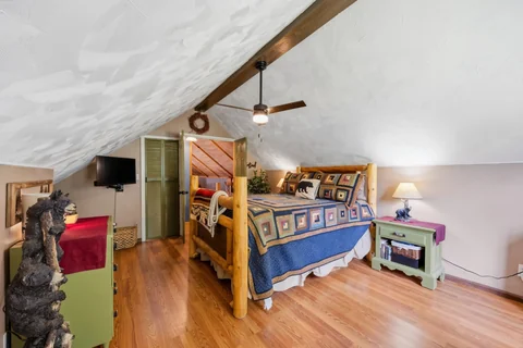 Upstairs bedroom with log bed and sloped ceiling