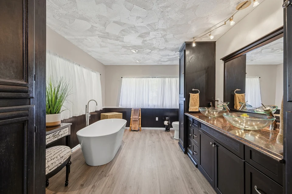 Bathroom with white freestanding tub and double vessel sinks